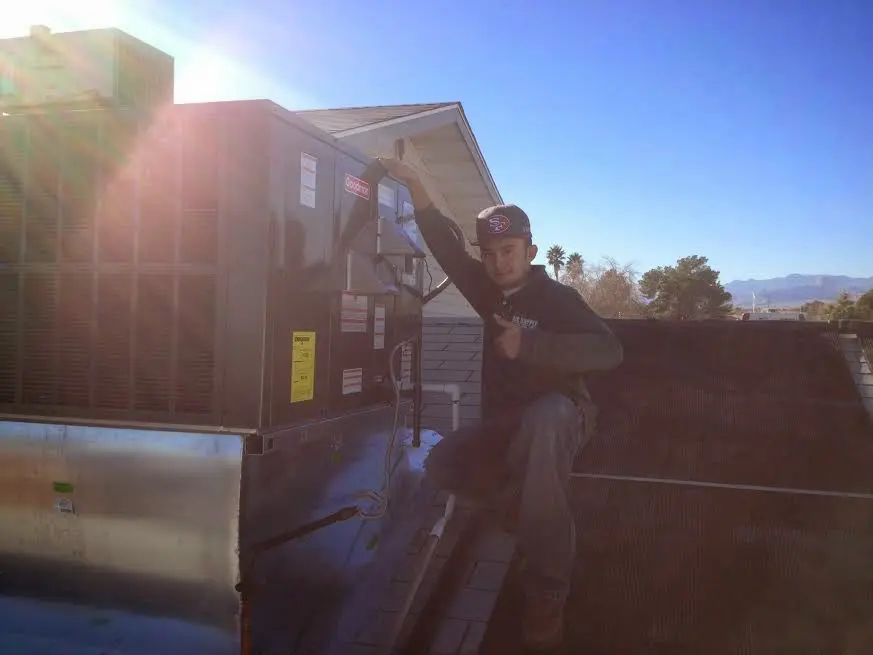 HVAC technician performing Boiler Repair on a rooftop unit in Peculiar